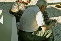 Възрастна двойка чете на пейка